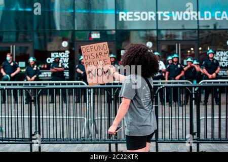 Barclays Center, Brooklyn am 4. Juni 2020. Eine junge Frau steht vor einer Menge bewaffneter Polizisten, die ein Schild aufwerfen und ihren Groll schreien Stockfoto