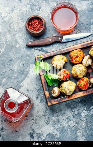 Gebackene Champignons gefüllt mit Käse auf Schneidebrett. Italienisches Essen. Party Snack Stockfoto