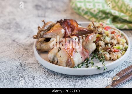 Köstliche gebackene Wachteln mit Speck und Beilage. Stockfoto