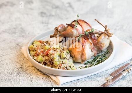 Köstliche gebackene Wachteln mit Speck und Beilage. Stockfoto