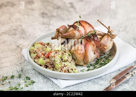 Köstliche gebackene Wachteln mit Speck und Beilage. Stockfoto