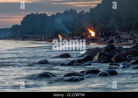 Nicht erkennbare Menschen feiern Sommersonnenwende mit Lagerfeuer am Strand Stockfoto