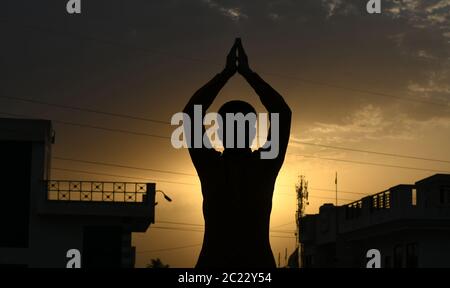 Beawar, Rajasthan, Indien, 16. Juni 2020: Silhouette einer Person, die "Surya Namaskar" Yoga während des Sonnenuntergangs vor dem 6. Internationalen Yoga-Tag, in Beawar. Yoga ist eine körperliche, geistige und spirituelle Praxis, die ihren Ursprung in Indien hat. Kredit: Sumit Saraswat/Alamy Live Nachrichten Stockfoto