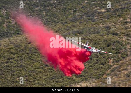 Winchester, CA USA - 14. Juni 2020: CAL Fire Aircraft fällt feuerhemmend auf einem trockenen Waldbrand auf einem Hügel in der Nähe von Winchester, Kalifornien. Stockfoto