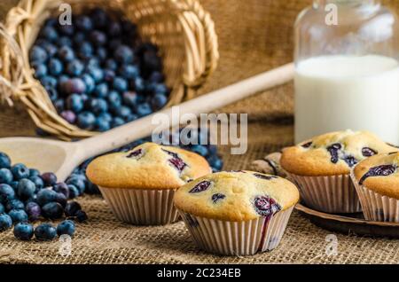 Blueberry Muffins Milch und Marmelade im Hintergrund und Korb voll mit Heidelbeeren Stockfoto
