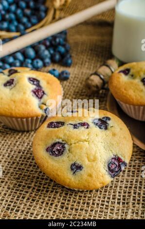Blueberry Muffins Milch und Marmelade im Hintergrund und Korb voll mit Heidelbeeren Stockfoto