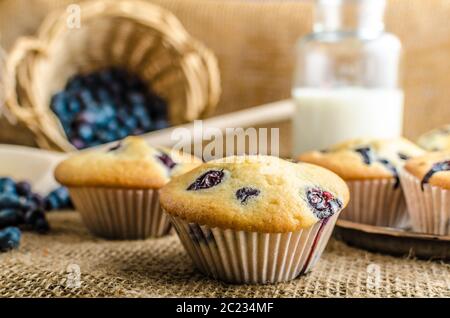 Blueberry Muffins Milch und Marmelade im Hintergrund und Korb voll mit Heidelbeeren Stockfoto