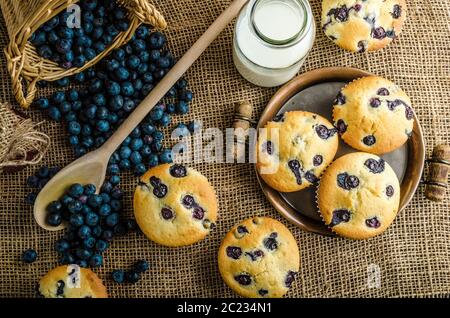 Blueberry Muffins Milch und Marmelade im Hintergrund und Korb voll mit Heidelbeeren Stockfoto