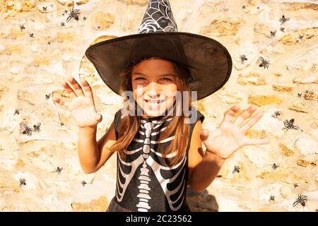 Portrait im Halloween Skelett Kostüm eines Mädchens mit gruseliger Handbewegung und Lächeln im Gesicht Stockfoto