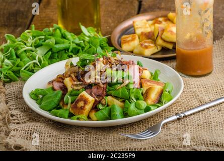 Kartoffel-Gnocchi mit Sommer-Salat, Speck und Röstzwiebeln. Gnocchi gekocht und dann auf Pfanne für Golden knusprig gebraten Stockfoto