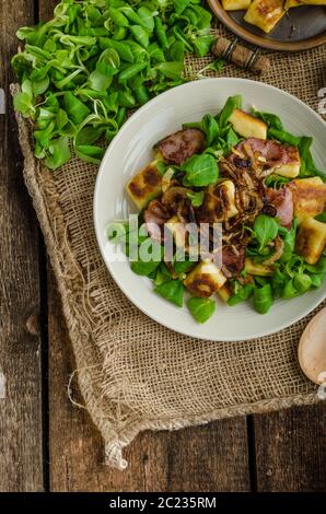 Kartoffel-Gnocchi mit Sommer-Salat, Speck und Röstzwiebeln. Gnocchi gekocht und dann auf Pfanne für Golden knusprig gebraten Stockfoto