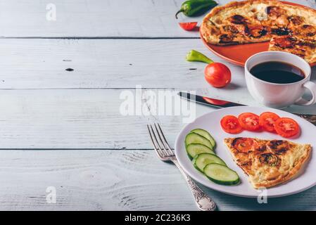 Frühstück frittata mit Chorizo, Tomaten und Chilischoten auf Teller und Tasse Kaffee über hellen Hintergrund. Gesundes Essen, das Konzept. Stockfoto