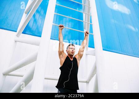 Athleten junge Sportler ziehen, mit schwarzen Sportswear, hören die Musik im Kopfhörer. Außerhalb. Stockfoto
