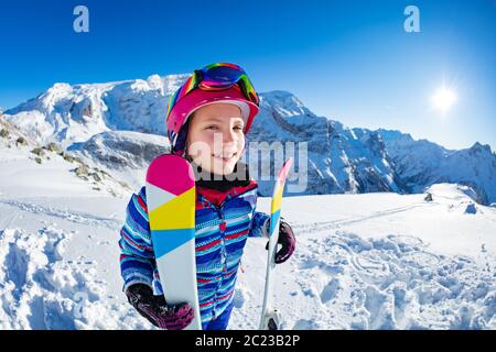 Fun Portrait von der Seite der lächelnden Skifahrer Mädchen mit Ski auf der Piste in rosa Maske und Farbbrillen stehen Stockfoto