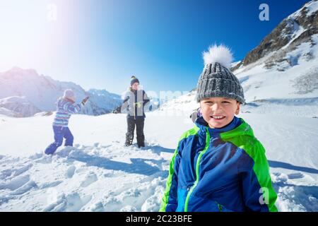 Portrait eines Jungen in den Winterbergen mit Mädchen spielen Schneeballschlacht auf Hintergrund Stockfoto