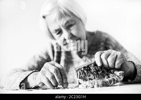 Betroffene ältere Menschen 96 Jahre alte Frau am Tisch zu Hause sitzen und zählen noch Münzen von der Pension in Ihrem Portemonnaie nach Rechnungen bezahlen. Unsustainabi Stockfoto