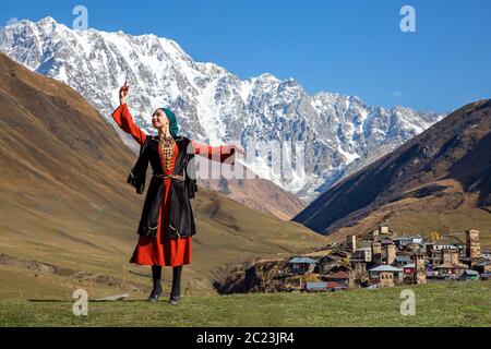 Georgische Frau in lokalen Svaneti Kostüme Durchführung traditionellen Tanz, mit Mount Shkhara im Hintergrund, in Ushguli, Georgien Stockfoto