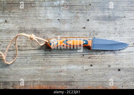 Handgeschmiedete Messer geschwärztem Stahl mit hausgemachten Epoxid- und orange Stoff Griff mit Lederband auf alten Holz- Board Stockfoto