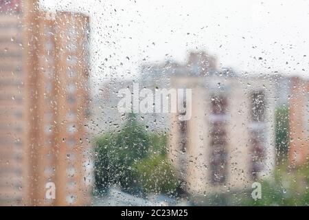 Regentropfen auf home Fenster Glas und verschwommenes Stadtbild auf den Hintergrund an regnerischen Herbsttag Stockfoto