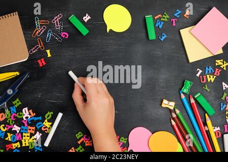 Weibliche Hand schreibt mit weißer Kreide auf einer Tafel, um den Umfang der Schule helle liefert, Ansicht von oben, zurück zur Schule Stockfoto