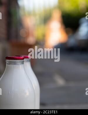 Nahaufnahme von Milchflaschen mit geringer Feldtiefe vor der Haustür Stockfoto