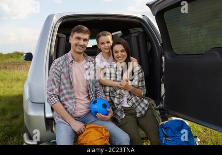 Glückliche Familie von Touristen mit Rucksäcken auf dem Hintergrund eines Autos auf die Natur. Stockfoto