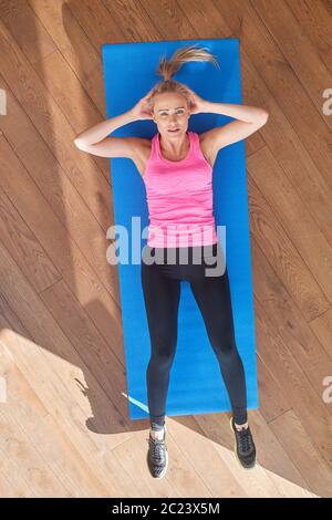 Fitness bestimmt mittleren Alters Frau liegend tun knirscht zu Hause auf Turnhalle Matte Stockfoto