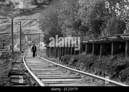 Frau, die auf einer alten Eisenbahnstraße aus Sowjetzeit in Atskuri, Georgien, unterwegs ist Stockfoto