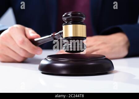 Judge's Hand Anschlagen der Hammer auf klingende Satz über Weiß Schreibtisch im Gerichtssaal Stockfoto