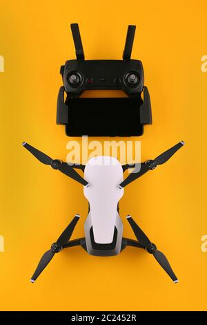 Drohne Quadcopter mit Fernbedienung und Smartphone ist bereit zu fliegen. Fernbedienung Drohne Dron Draufsicht auf isolierten gelben Hintergrund. Flach legen Drohne o Stockfoto