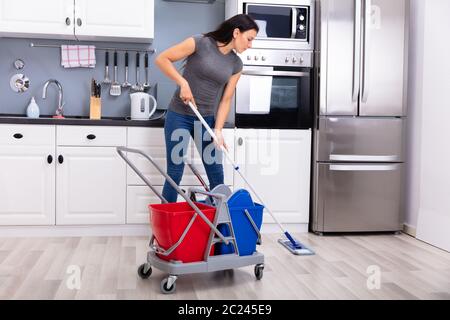 Gerne weibliche Hausmeister Reinigung Boden mit Mop In der Küche Stockfoto