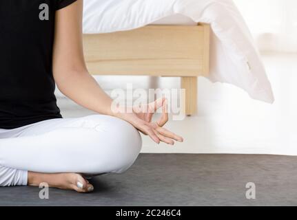 Attraktive asiatische Frau trägt Sportbekleidung Meditation Yoga auf Matte in weißen Schlafzimmer, tun erreicht Pose oder Siddhasana Asana in der morn Stockfoto