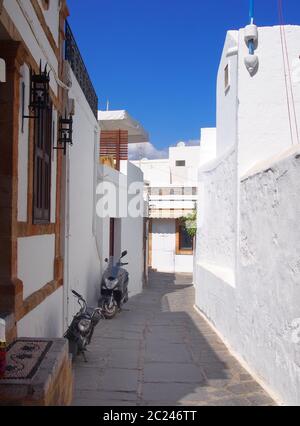 Weiß getünchte Dorfstraße in afandou auf rhodos mit blauen Scheuklappen und Motorrädern Stockfoto