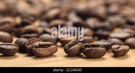 Körner gerösteter Kaffees auf dem Tisch, Nahaufnahme mit unscharfem Hintergrund Stockfoto
