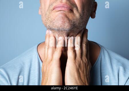 Close-up In eines Mannes Hand berühren Ihr Halsschmerzen Stockfoto