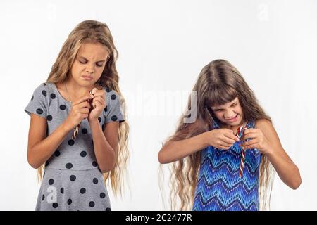 Zwei Mädchen versuchen, eine Plastiktüte mit Karamell Bonbons zu öffnen. Stockfoto