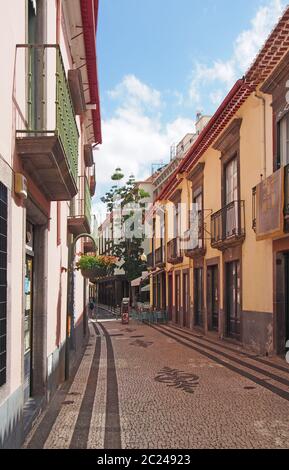 Eine ruhige gepflasterte Straße in funchal madeira mit einem Hotel im traditionellen Stil und Cafe mit Balkonen und bemalten Häusern Stockfoto