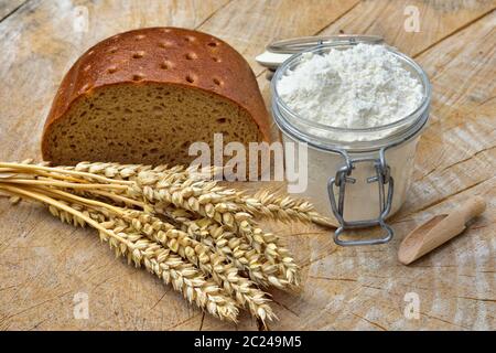 Mehl, Brot und Getreide auf einem Holzbrett. Stockfoto