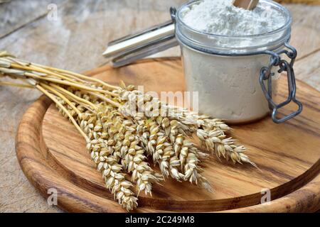 Mehl, Brot und Getreide auf einem Holzbrett. Stockfoto