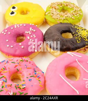 Sechs Runden verschiedene süße Krapfen mit Streuseln in einem Papier, das weisse Feld, Ansicht von oben, selektiver Fokus Stockfoto