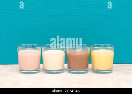 Aromatisiert Milchshakes - Erdbeere, Schokolade und Banane - und frische, cremige Milch in Glas Trinkgläser gegen eine blaugrüne Hintergrund Stockfoto