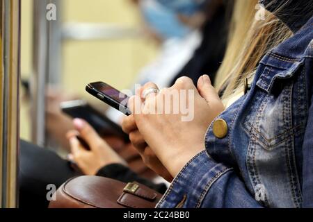 Menschen nutzen Smartphones sitzen in U-Bahn-Auto. Handy in weiblichen Händen Nahaufnahme, Konzept der Online-sucht, sms, Social Media Stockfoto