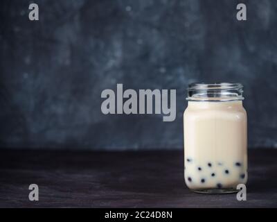 Hausgemachte Milch Bubble Tea mit Tapioka Perlen Kugeln. Beliebte Taiwan Bubble Tea in Glas Marmeladenglas mit Kopie Platz für Text. Bubble Tea auf dunklen backgrou Stockfoto