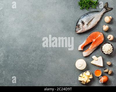 Vaitamin D Sources Konzept mit Kopierraum für Text. Fisch, Lachs, Milchprodukte, Eier, Pilze auf grauem Steingrund. Draufsicht oder flaches Lay. Cop Stockfoto