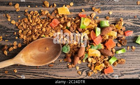 Haferflocken mit Honig Nüsse und getrocknete Früchte im Ofen gebacken. Morgen Farbvergnügen. Portion Müsli auf einem Holzlöffel Stockfoto