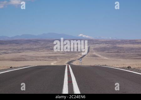 Die unendliche Straße führt durch eine ungekrönte, einsame Landschaft Stockfoto