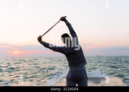 Rückansicht des Menschen in Sportkleidung Übungen mit Seil springen, Training auf Pier, in der Nähe des Meeres. Stockfoto