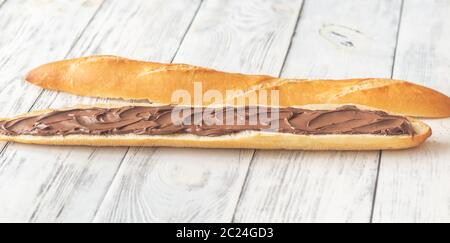 Die Hälfte der Baguette mit Schokoladencreme auf dem hölzernen Tisch Stockfoto