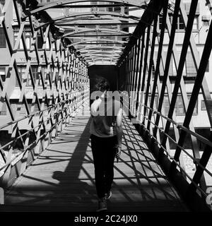 Rückansicht eines jungen Mädchens mit flatternden Haare zu Fuß über die Pont de les Peixateries Velles, durch G. Eiffel in Girona, Katalonien, Spanien Stockfoto