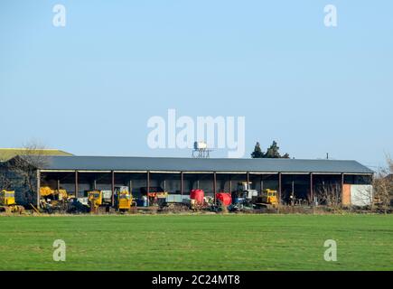 Traktoren und andere Geräte unter der Markise in der Garage Stockfoto